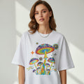 Model wearing a white t-shirt with colorful mushroom design on a light gray background
